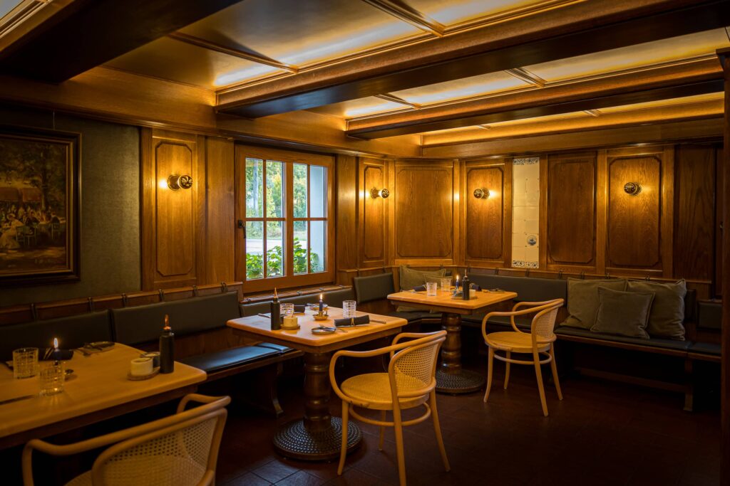 Innenansicht eines Restaurants mit Holzmöbeln, Tischen und Stühlen in einem gemütlichen Ambiente.