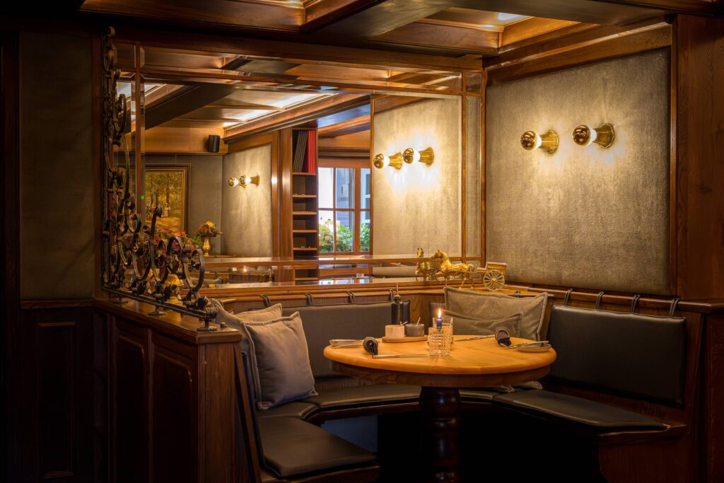 Gemütliche Sitzecke mit einem runden Holztisch und gepolsterten Bänken in einem Restaurant.