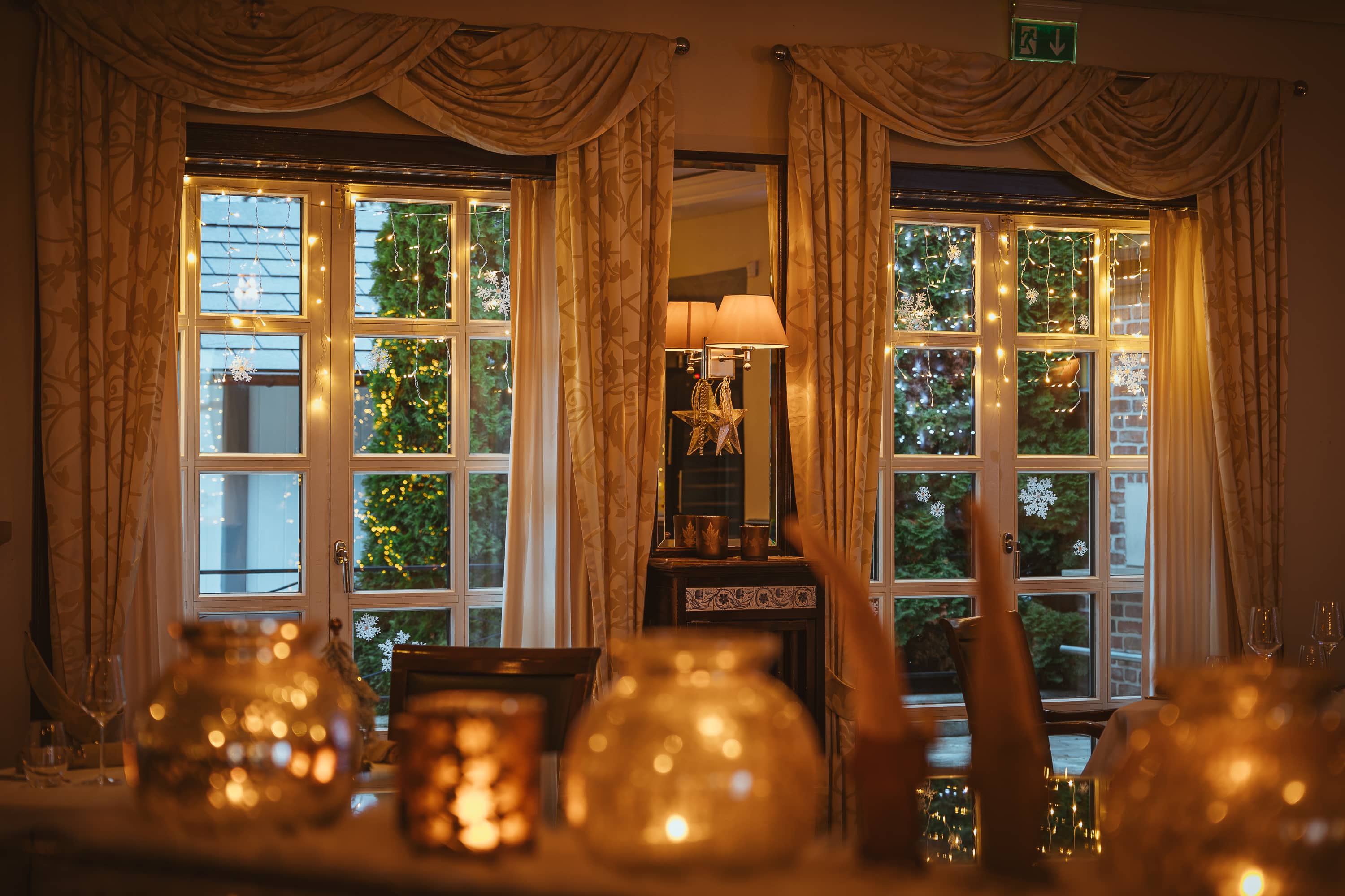 Fenster mit warmem Licht und dekorativen Vorhängen in einem Restaurant mit festlicher Atmosphäre.