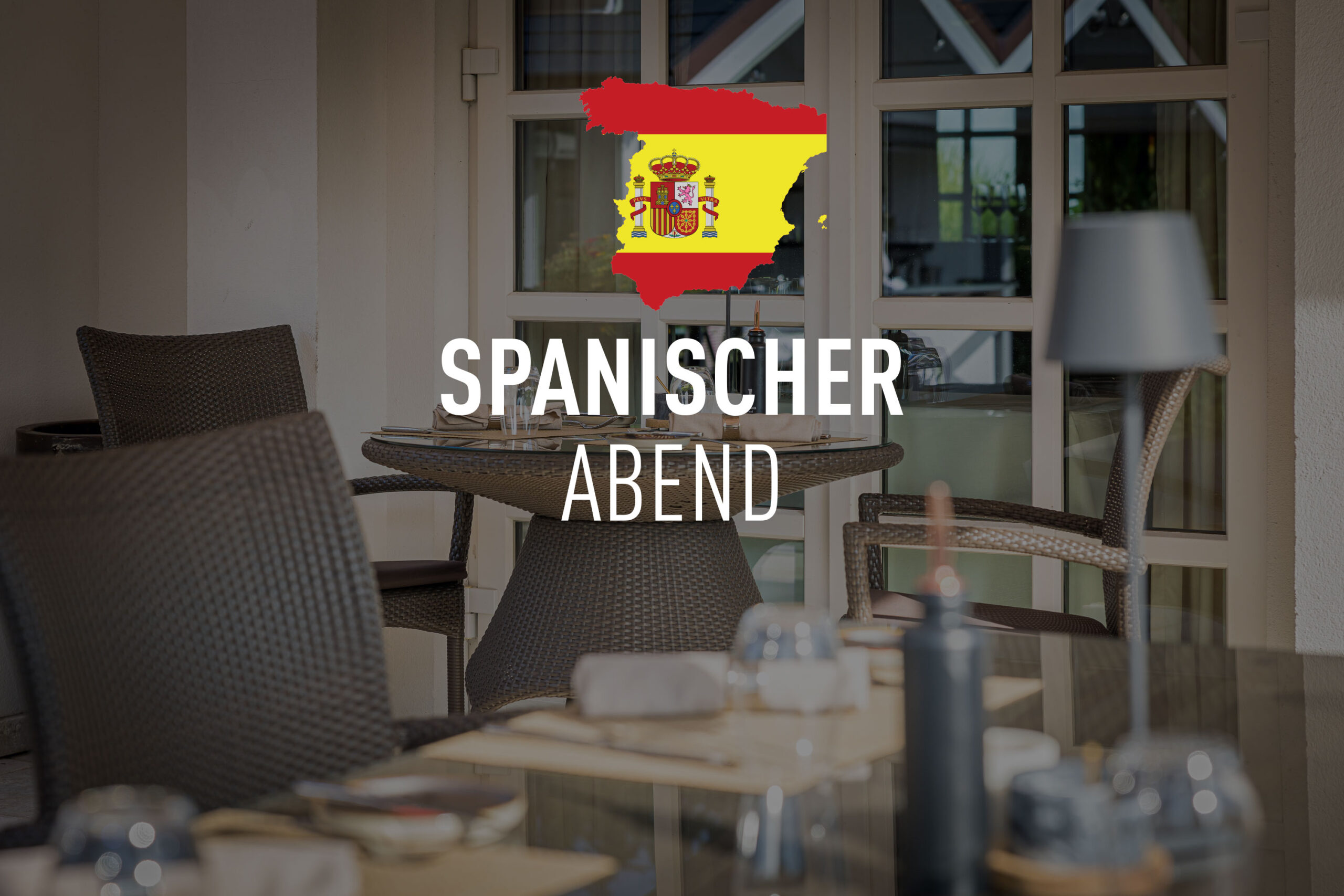 Ein gedeckter Restaurantbereich mit Glasfront und dem Schriftzug „Spanischer Abend“ vor einer Spanien-Flagge.